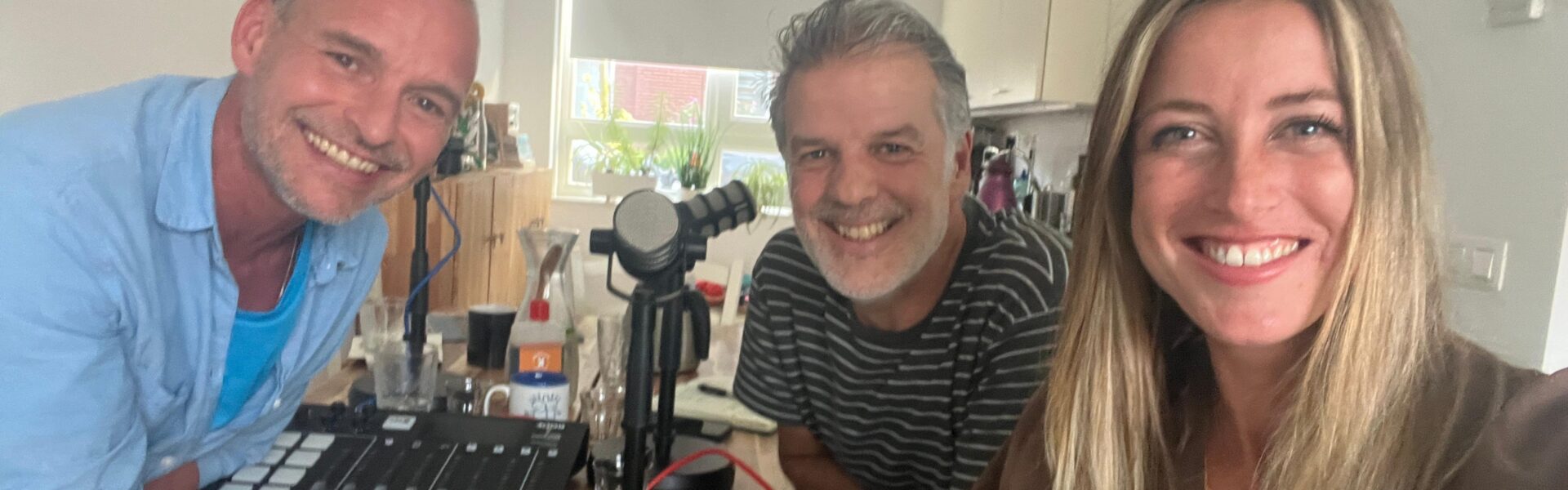 Twee oudere mannen en een jonge vrouw kijken lachend in de camera