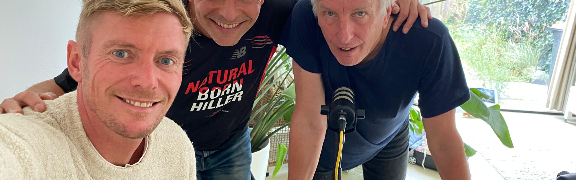 Jordy, Jose en hans kijken vrolijk in de camera. Jordy is een jonge man met kort blond haar. Jose en Hans zijn ouder. Jose is kalend en hans heeft grijs haar.